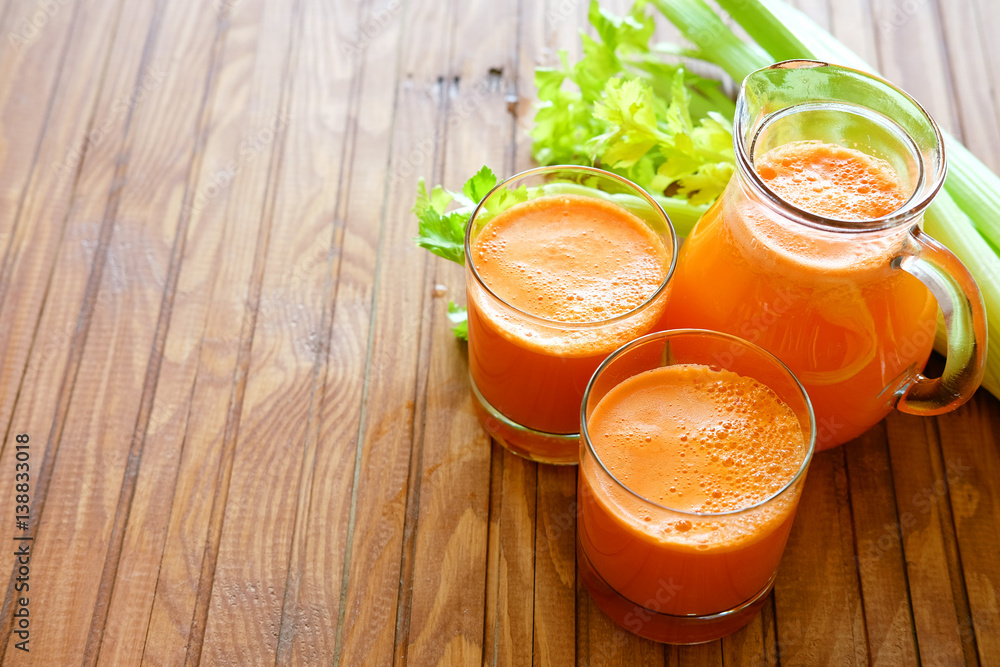 Fresh carrot juice poured into glasses and green celery Fresh carrot juice poured into glasses and green celery