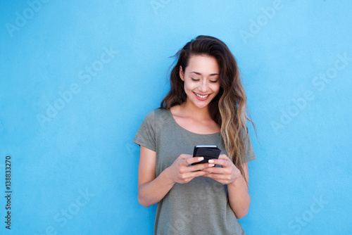 young smiling woman using mobile phone against blue background photo
