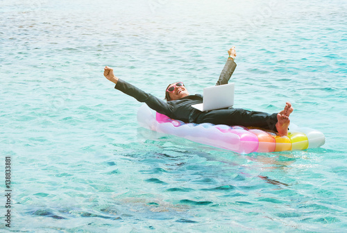 Valokuva Happy businesswoman resting on lilo with laptop
