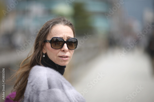 Portrait of a woman in sunglasses and fur jacket.