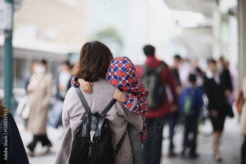 Photography A woman with a sleeping baby in her arms on a city street. Japan.
