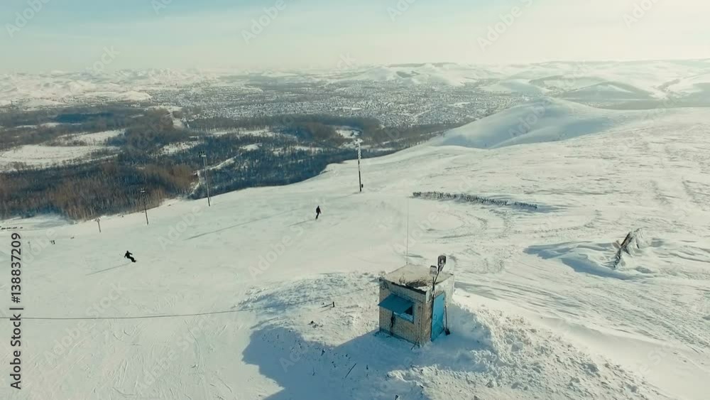 Several people ride away from the ski-lift. Several people ride away from the ski-lift.