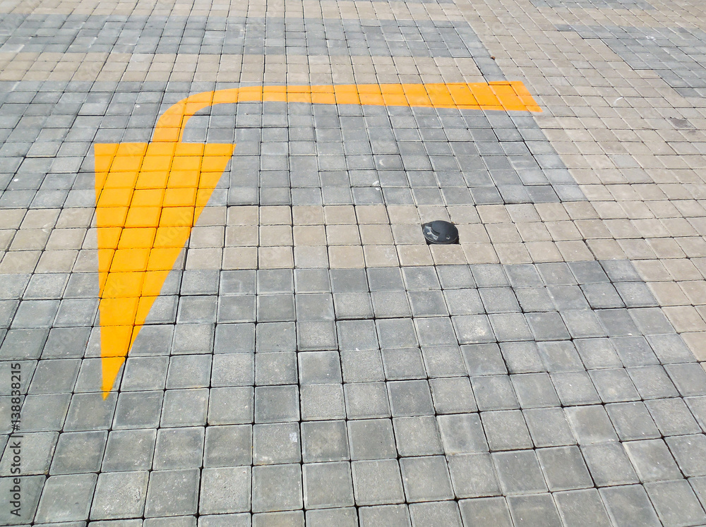 Soft focused picture of  Yellow arrow painted in a brick road. Showing which way should turn  your car.