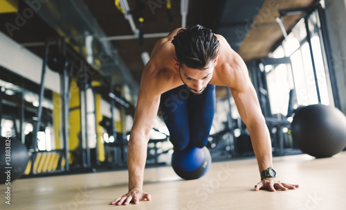 Fototapeta Naklejka Na Ścianę i Meble -  Sporty athlete doing push ups in gym