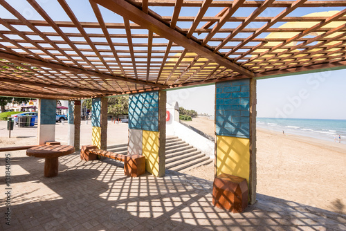 Fototapeta Naklejka Na Ścianę i Meble -  Seating under a colorful lattice framed structure near the beach
