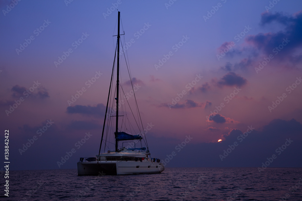 Catamaran on open ocean in dark sunset light