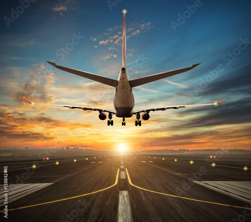 Airplane landing to airport runway in sunset light photo