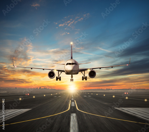 Airplane landing to airport runway in sunset light