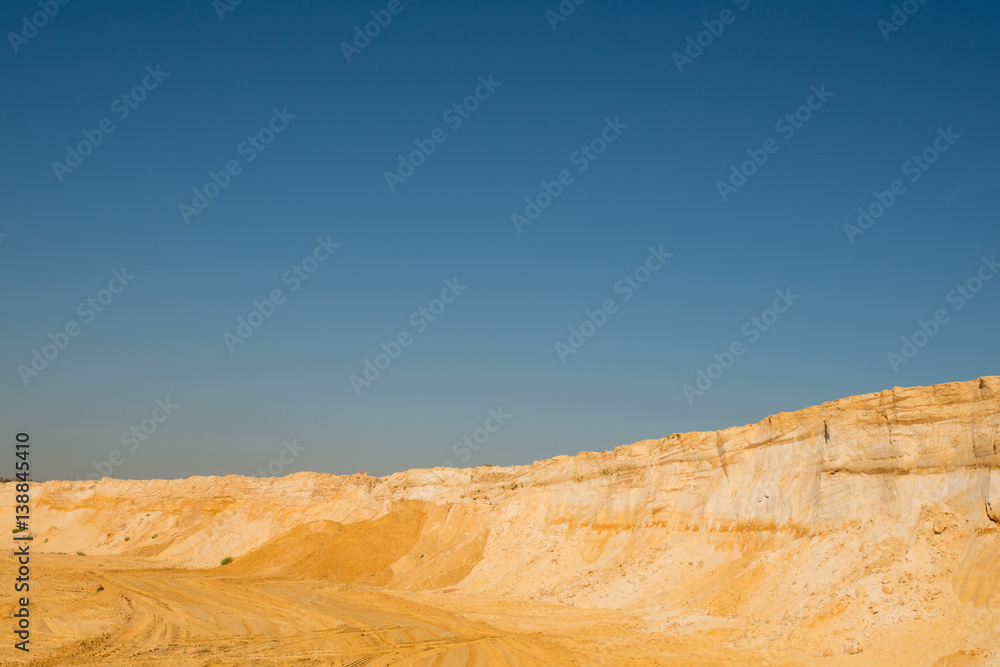 cliff of the yellow orange brown sand soil clay under the bright sunny day with deep blue sky