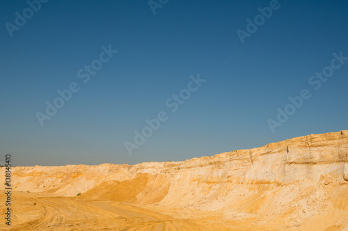 cliff of the yellow orange brown sand soil clay under the bright sunny day with deep blue sky