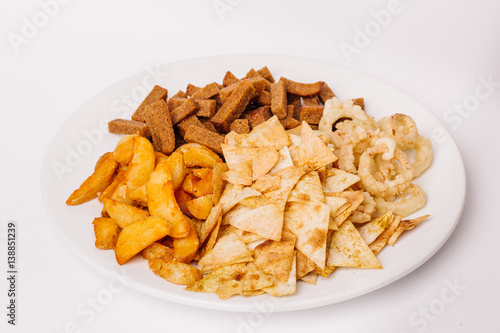 Fast food snacks composition with onion rings   crackers  baked potatoes  chips  toast.