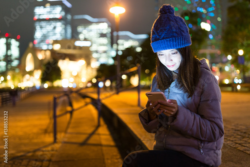 Woman using mobile phone at night in Yokohama