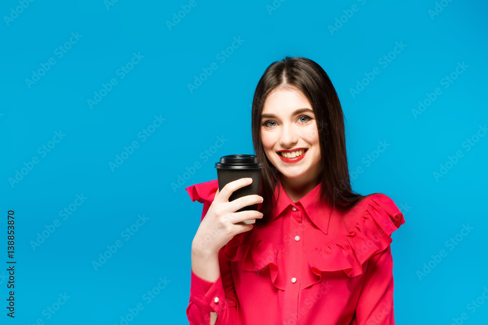 Fashion pretty woman with coffee cup in colorful clothes over blue background wearing a pink Fashion pretty woman with coffee cup in colorful clothes over blue background wearing a pink