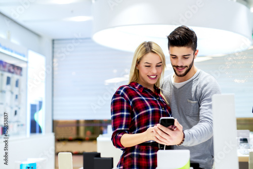 Couple at mobile store buying new smart phone. Shopping concept at shopping mall.