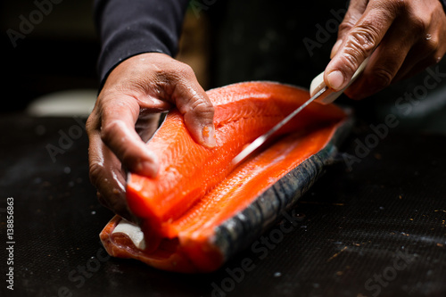 Hands of a male filleting salmon 
