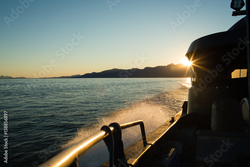 Boat travelling on sea at sunset  photo