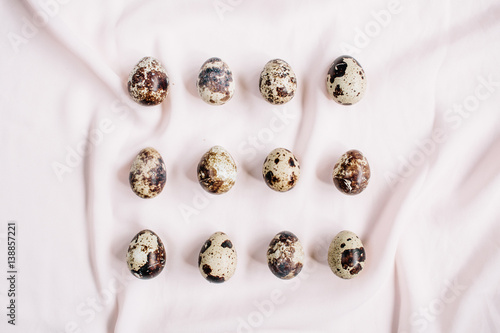 Quail eggs on pink textile background. Flat lay, top view. Easter concept.