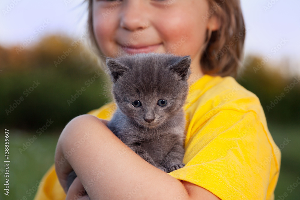kitten on arm of the boy outdoors, child huge his love pet