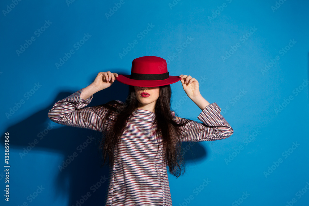 Fashion Brunette Lady in red hat and red lips on blue background Fashion Brunette Lady in red hat and red lips on blue background