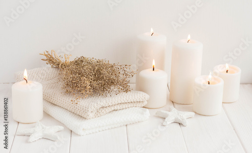Spa composition with candles, sea salt and flowers on white wooden background.
