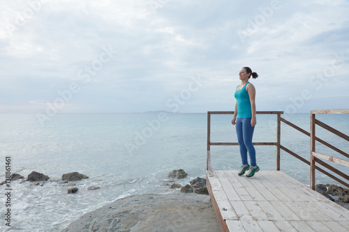 Young woman standing on wooden bridge by the sea