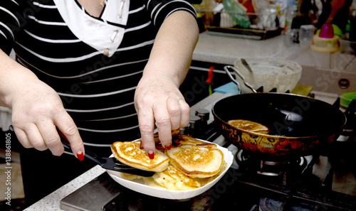 Senior woman heands fry pancakes in the house photo