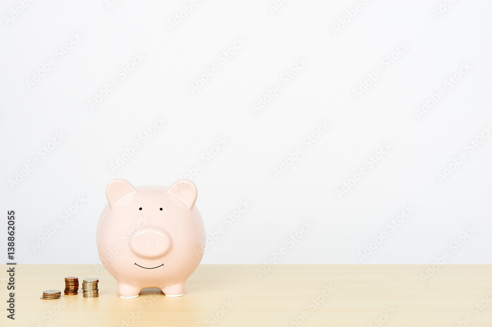 Piggybank on wooden table with stacks of coins beside it. Piggybank on wooden table with stacks of coins beside it.