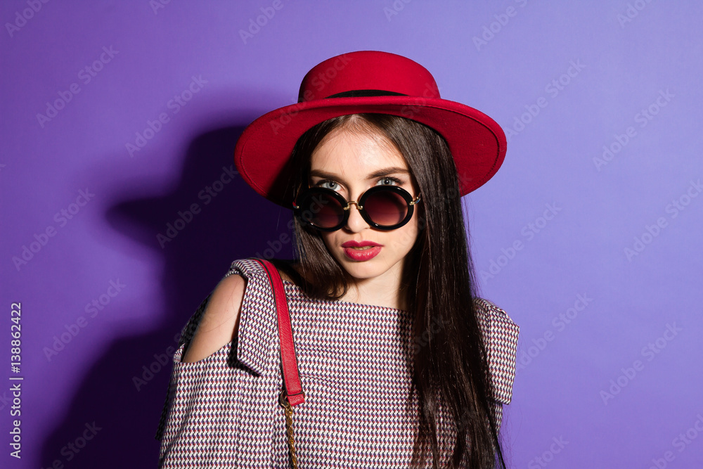 Lovely model in fashionable red Hat and a red Clutch on blue background Lovely model in fashionable red Hat and a red Clutch on blue background