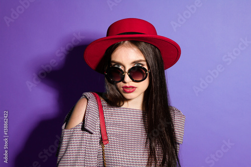Lovely model in fashionable red Hat and a red Clutch on blue background