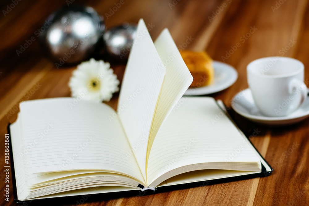 Notizbuch, Croissant und Kaffeetasse auf Holztisch