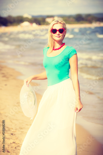 Blonde woman wearing dress walking on beach