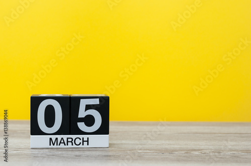 March 5th. Day 5 of month, calendar on table with yellow background. Spring time, empty space for text