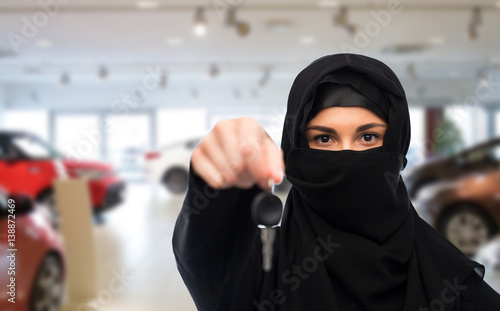 muslim woman in hijab with car key over car show