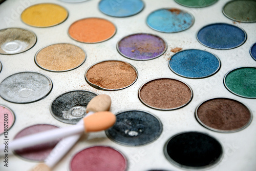 Close-up of multi-colored eyeshadow palette and make up brushes