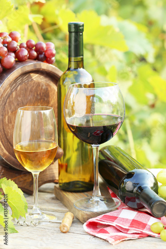 Wine in glasses with bunch of grape on wooden table
