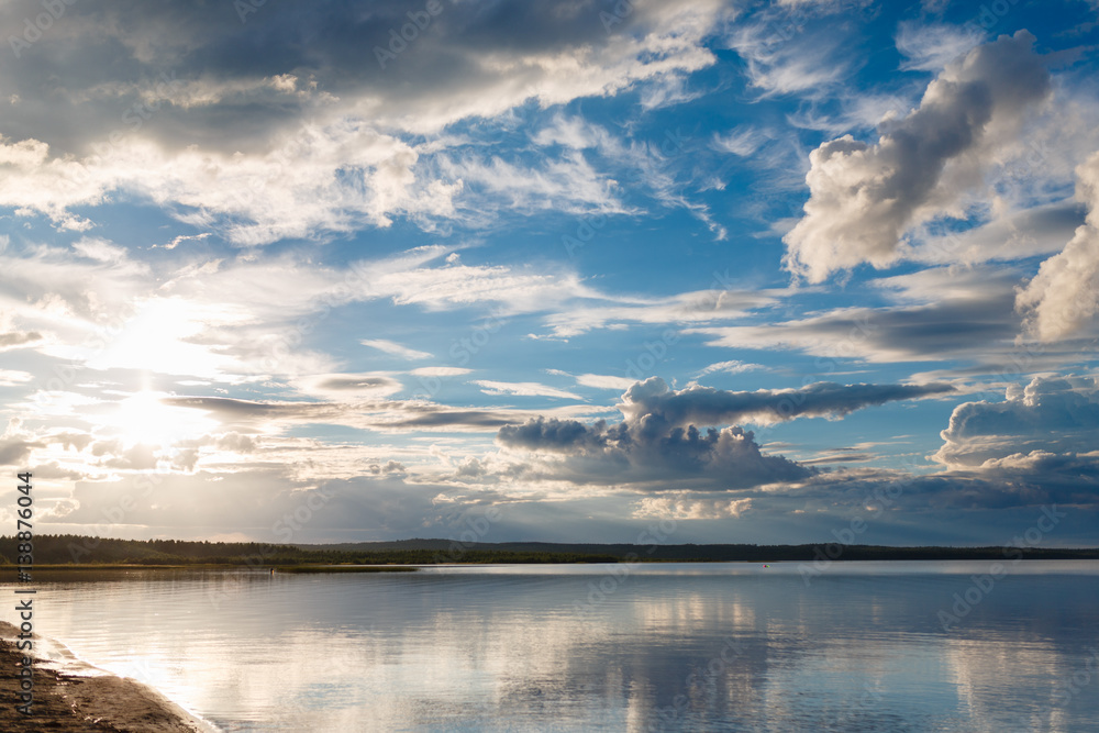 Beautiful sunset on the lake, the clouds reflected in the water. Surface on the lake. Russia, Karelia. Wide photo
