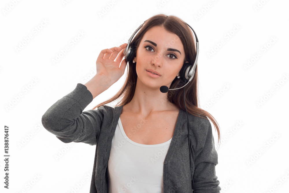 beautiful young girl in headphones with MIC looks into the camera and holds his hand near the ear beautiful young girl in headphones with MIC looks into the camera and holds his hand near the ear