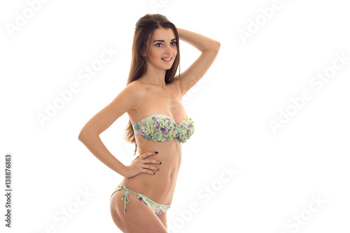young beautiful girl in bathing suit with big breasts worth turning sideways keeps his hand on the side and smiling