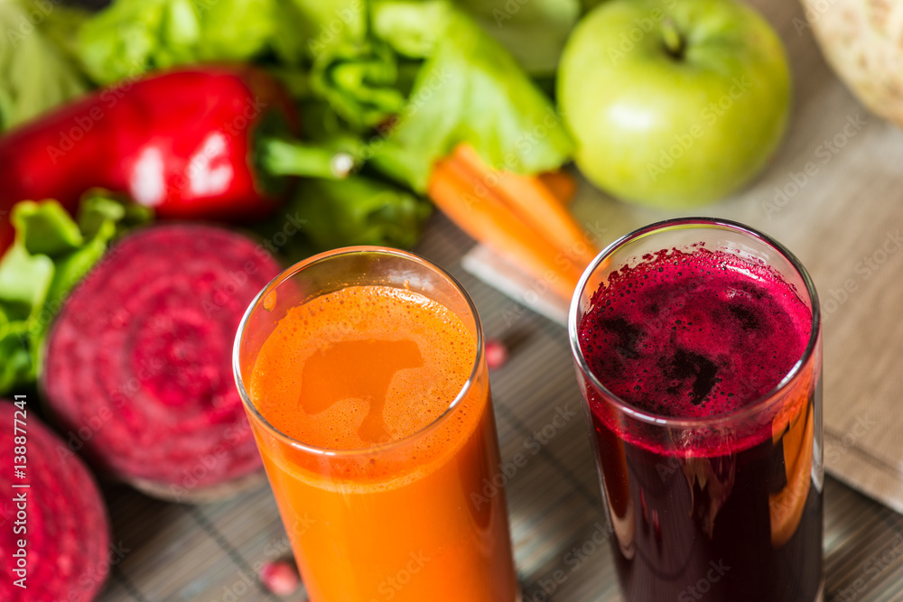 two glasses of different fresh juice. Beet and carrot juices on grey wood background two glasses of different fresh juice. Beet and carrot juices on grey wood background