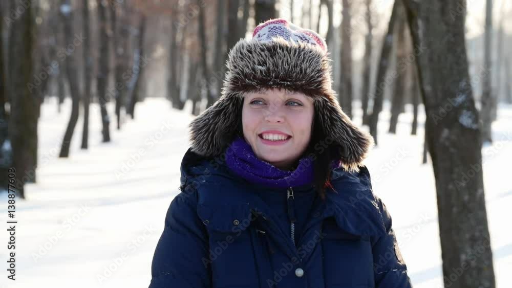 Woman looking around in winter park, smiling straight to camera. Woman looking around in winter park, smiling straight to camera.