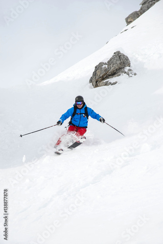 Skifahrer im Tiefschnee mit Felsen
