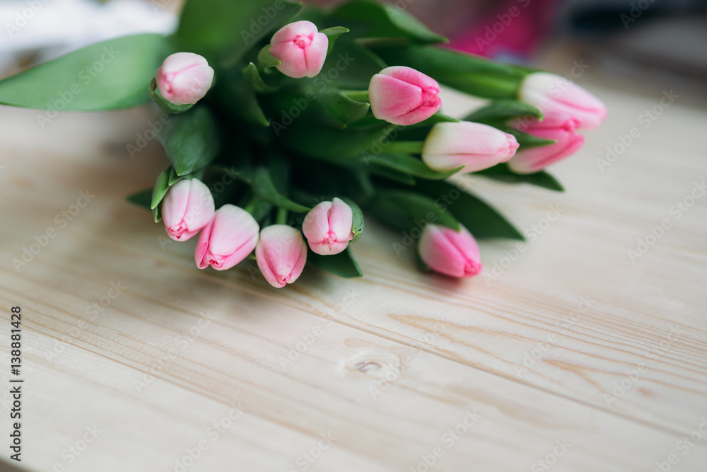 Pale pink tulips lie on a wooden table. Flowers as a gift. Pale pink tulips lie on a wooden table. Flowers as a gift.
