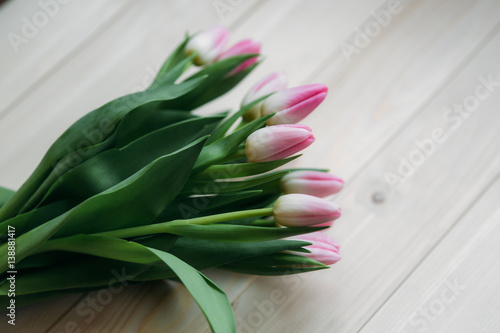 Pale pink tulips lie on a wooden table. Flowers as a gift.