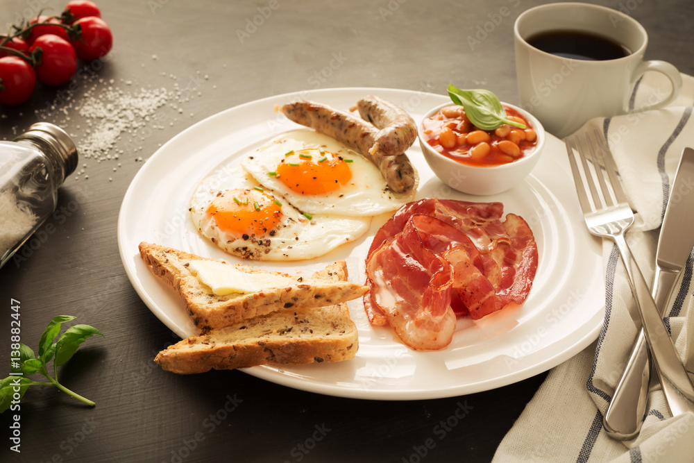 Full english breakfast on white plate, black background. Full english breakfast on white plate, black background.