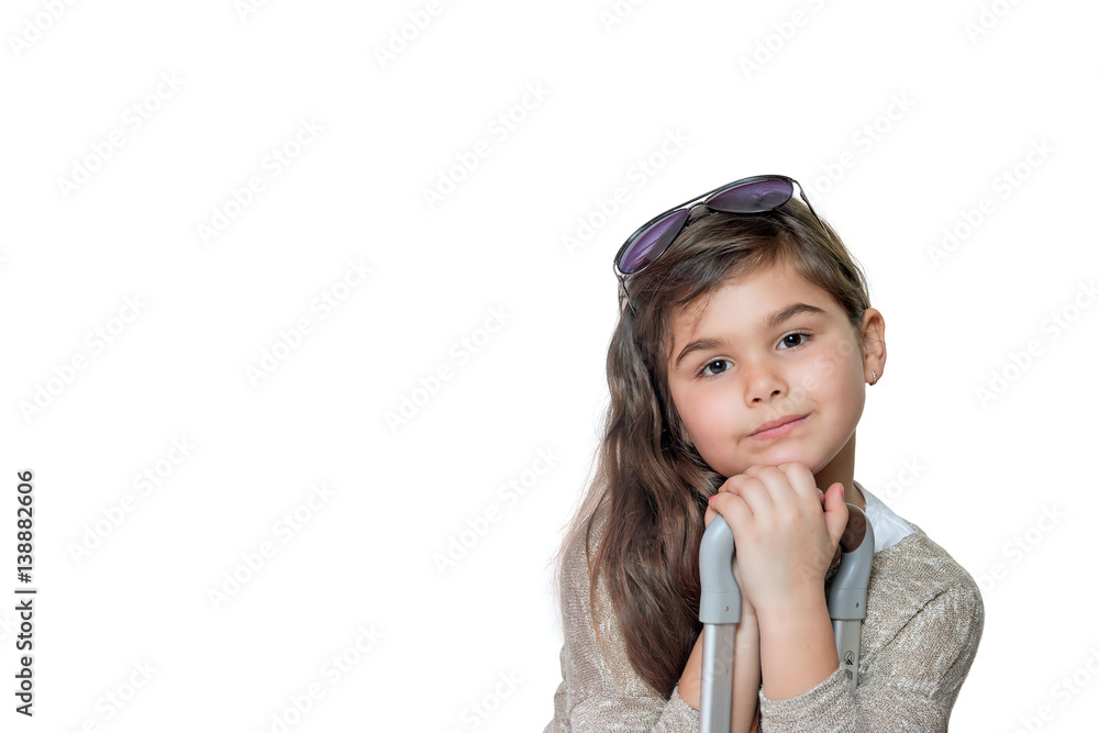 Studio shot of cool little girl tourist with glasses on her head leaning on the handle of a suitcase and looking at the camera. All is on the white background. Studio shot of cool little girl tourist with glasses on her head leaning on the handle of a suitcase and looking at the camera. All is on the white background.