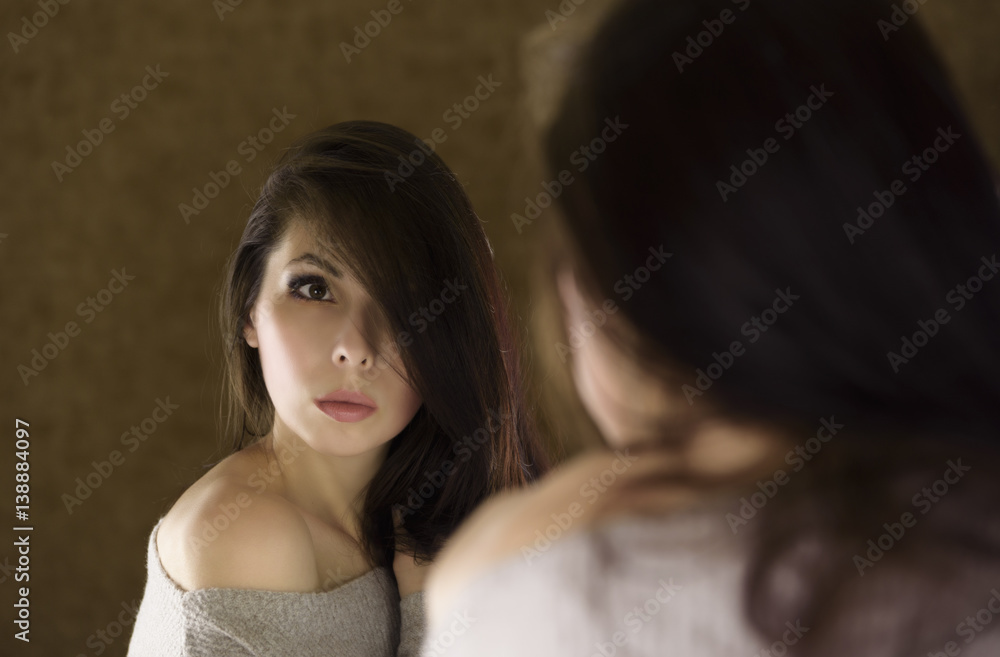 Sad woman looking in the mirror. Reflection of a woman in the mirror. Sad woman looking in the mirror. Reflection of a woman in the mirror.