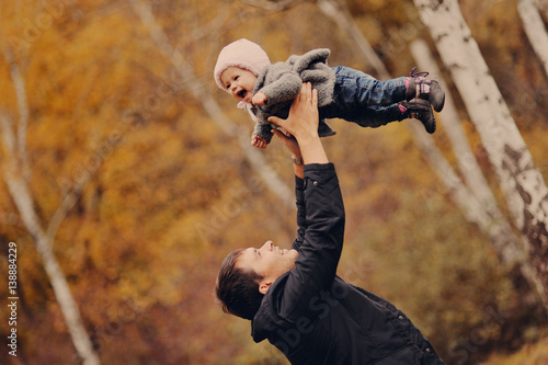 Молодой отец играет со своей маленькой дочерью в осеннем парке