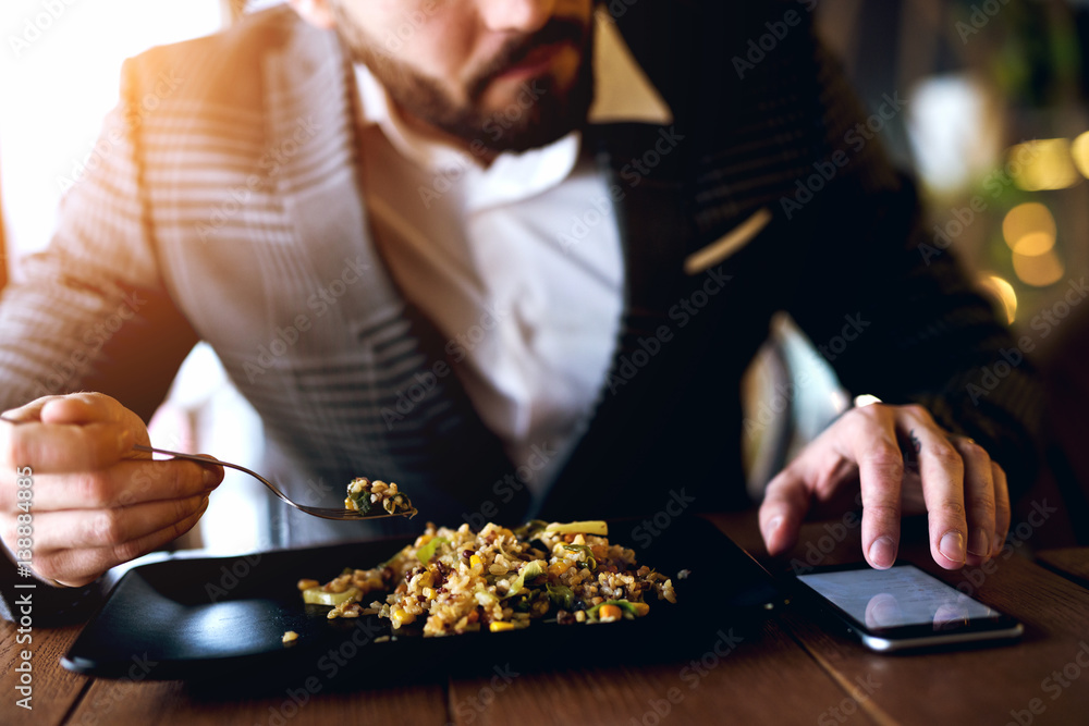 Busy man checking phone for messages while having short lunch. Busy man checking phone for messages while having short lunch.