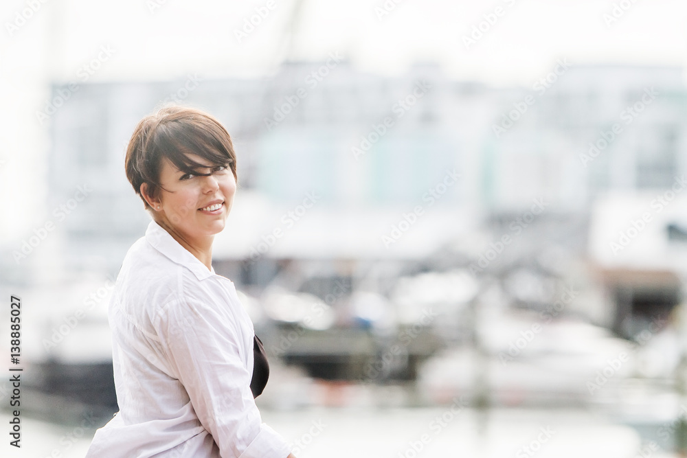 Fototapeta premium outdoor portrait of young happy smiling woman on urban city background