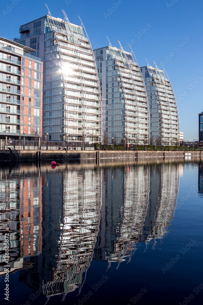 Reflections on a tranquil water during a day from a sunny lit on residential buildings.